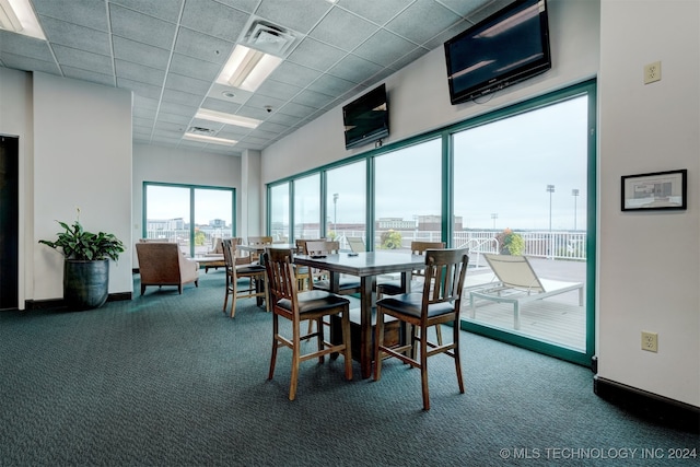 carpeted dining area with a drop ceiling