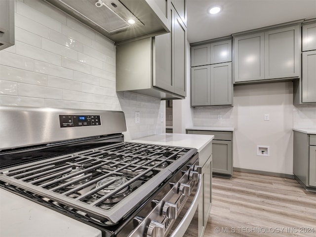 kitchen with gray cabinets, light wood-type flooring, and stainless steel gas range oven