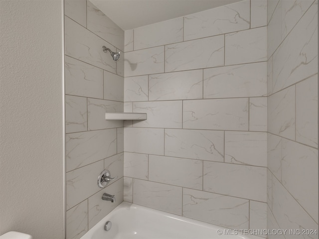 bathroom with toilet and tiled shower / bath