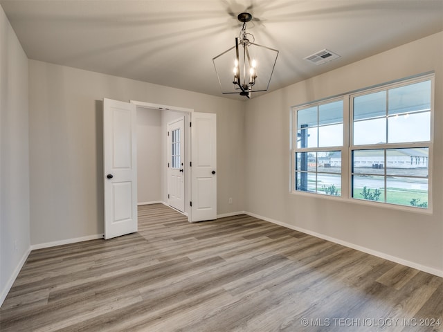 unfurnished room with light hardwood / wood-style flooring and a notable chandelier