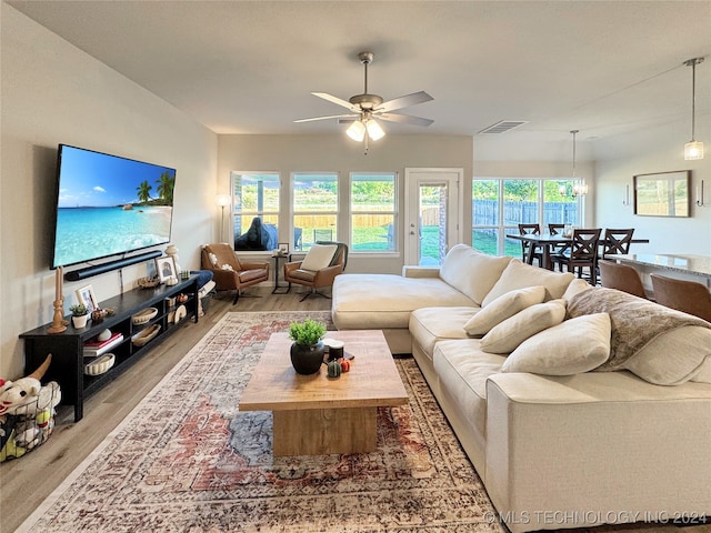 living room with ceiling fan with notable chandelier and light hardwood / wood-style floors