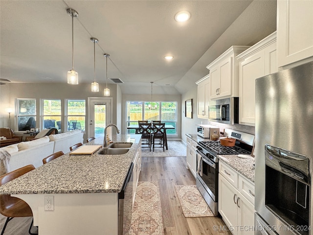 kitchen with lofted ceiling, light hardwood / wood-style flooring, appliances with stainless steel finishes, a kitchen bar, and a center island with sink