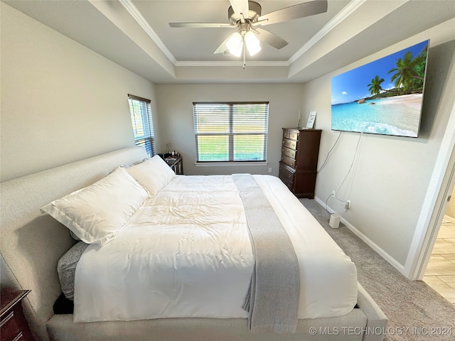 bedroom featuring ceiling fan, a tray ceiling, crown molding, and carpet flooring