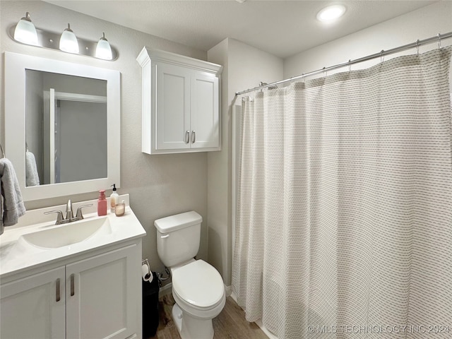 bathroom with hardwood / wood-style floors, a shower with shower curtain, vanity, and toilet