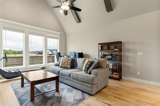 living room with high vaulted ceiling, light wood-type flooring, ceiling fan, and a healthy amount of sunlight