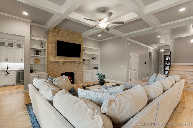 living room with light hardwood / wood-style floors, coffered ceiling, a fireplace, beamed ceiling, and ceiling fan