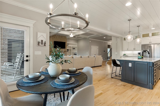 dining area featuring light wood-type flooring, crown molding, an inviting chandelier, and sink