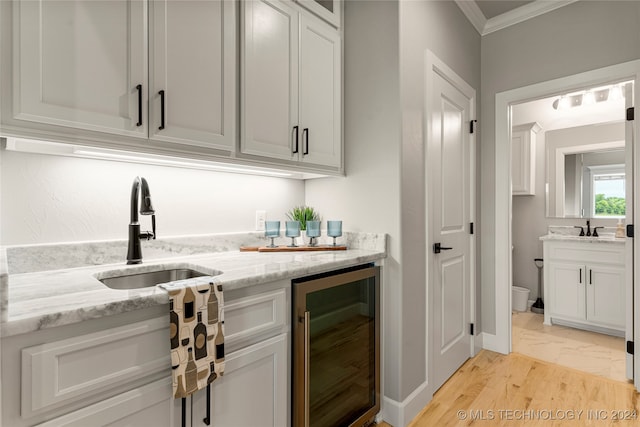 bar featuring wine cooler, white cabinets, light stone countertops, light hardwood / wood-style flooring, and sink