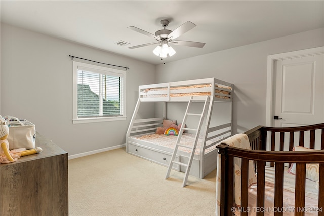 bedroom featuring light carpet, ceiling fan, and a nursery area