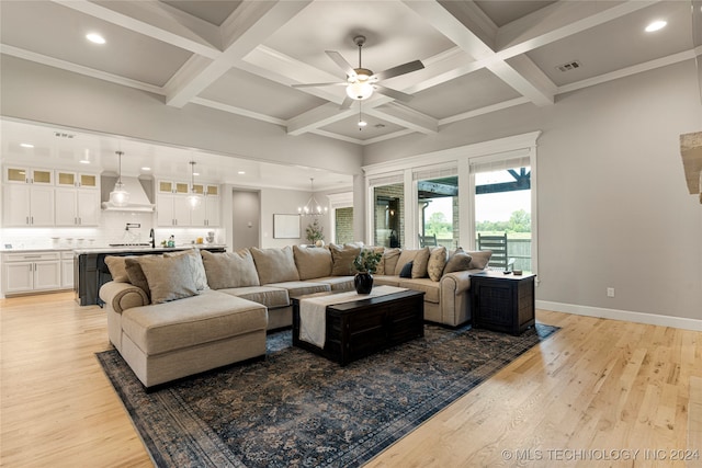 living room with ceiling fan with notable chandelier, beamed ceiling, light wood-type flooring, and ornamental molding