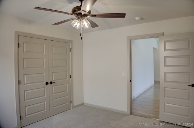 unfurnished bedroom featuring light carpet, a closet, and ceiling fan