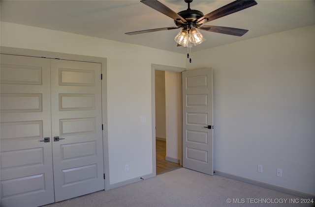 unfurnished bedroom featuring light carpet, ceiling fan, and a closet