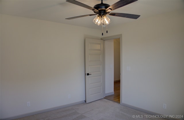 spare room with ceiling fan and light colored carpet