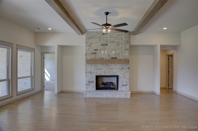 unfurnished living room featuring ceiling fan, light hardwood / wood-style flooring, a fireplace, and beam ceiling