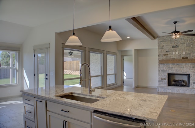 kitchen featuring white cabinetry, light stone counters, ceiling fan, stainless steel dishwasher, and sink