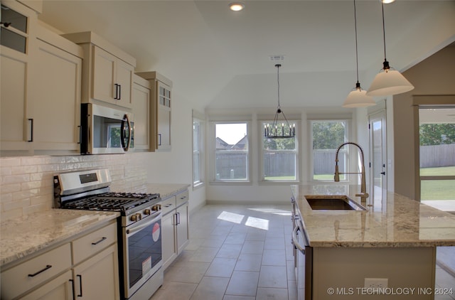 kitchen featuring an island with sink, appliances with stainless steel finishes, sink, and vaulted ceiling