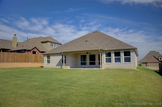 rear view of property featuring ceiling fan, a yard, and a patio area