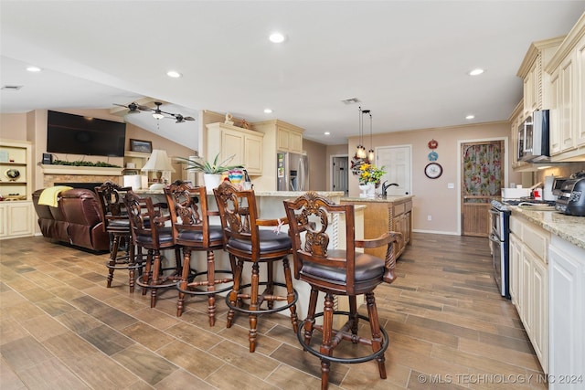 kitchen with hanging light fixtures, a breakfast bar, appliances with stainless steel finishes, and light stone counters