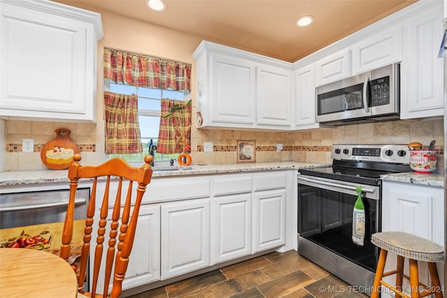 kitchen with stainless steel appliances, white cabinets, and light stone countertops