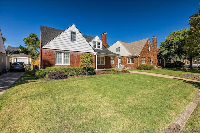 new england style home with a front yard, cooling unit, a garage, and an outbuilding