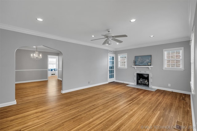 unfurnished living room featuring light wood-type flooring, ceiling fan with notable chandelier, crown molding, and a wealth of natural light