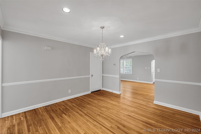 spare room featuring a notable chandelier, light wood-type flooring, and ornamental molding