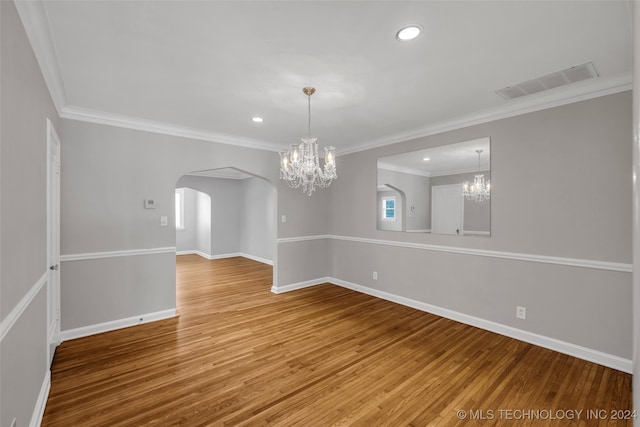 unfurnished room with wood-type flooring, crown molding, and a chandelier