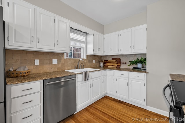 kitchen with stove, white cabinets, light hardwood / wood-style floors, and stainless steel dishwasher