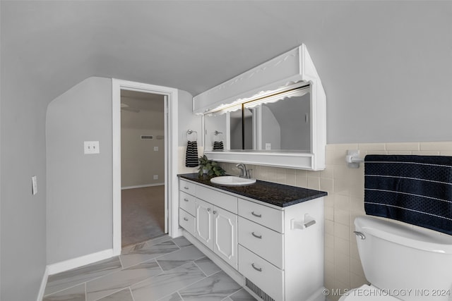 bathroom featuring tile walls, vanity, and toilet