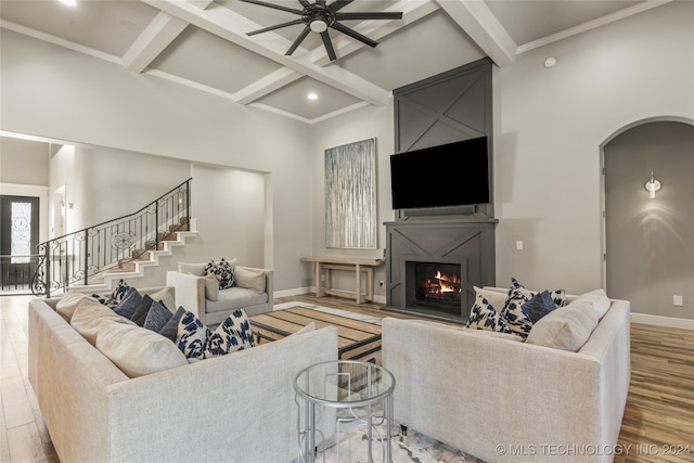 living room featuring ornamental molding, coffered ceiling, ceiling fan, wood-type flooring, and beamed ceiling