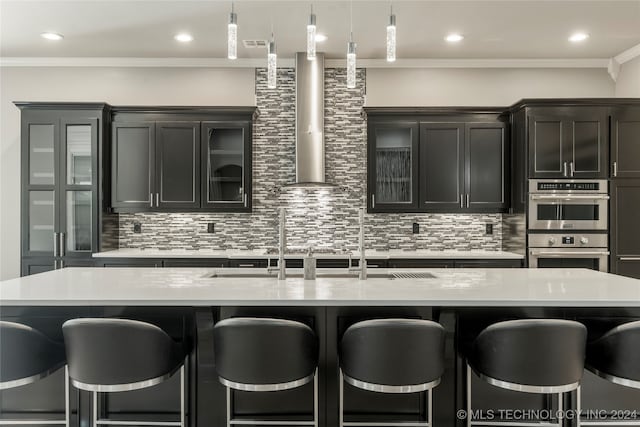 kitchen with a center island with sink, decorative light fixtures, backsplash, and a breakfast bar area