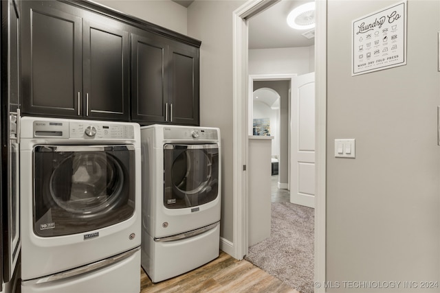 laundry area with washer and clothes dryer, cabinets, and light hardwood / wood-style flooring