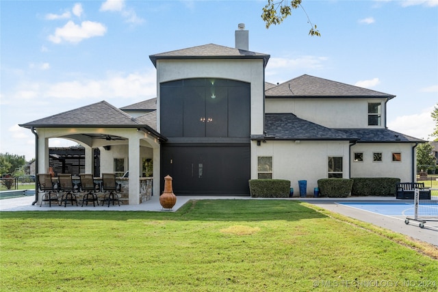 rear view of property with a lawn, ceiling fan, and an outdoor bar