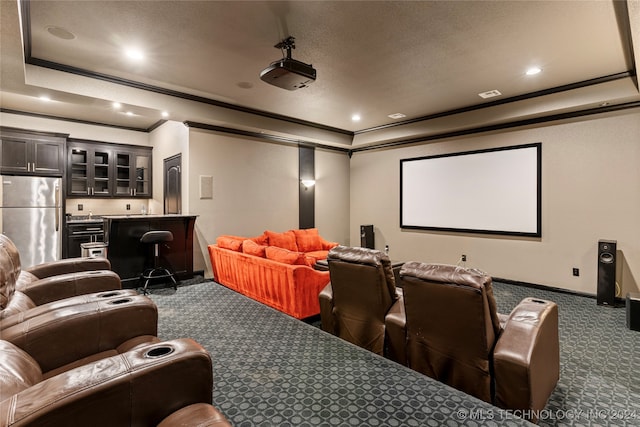 carpeted home theater with a tray ceiling, crown molding, and indoor bar