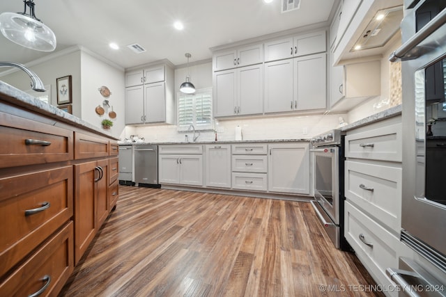 kitchen featuring appliances with stainless steel finishes, white cabinets, pendant lighting, ornamental molding, and dark hardwood / wood-style floors