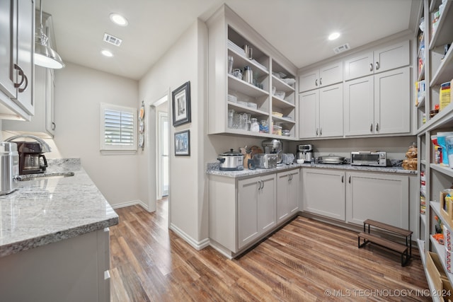 kitchen with sink, dark wood-type flooring, and light stone counters