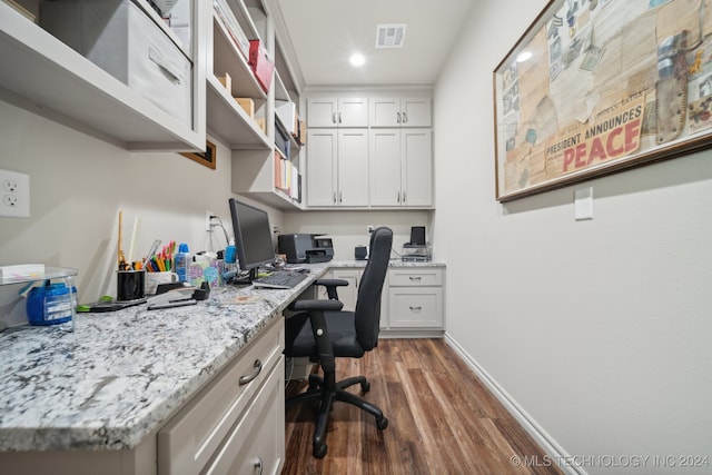 home office with built in desk and dark hardwood / wood-style floors