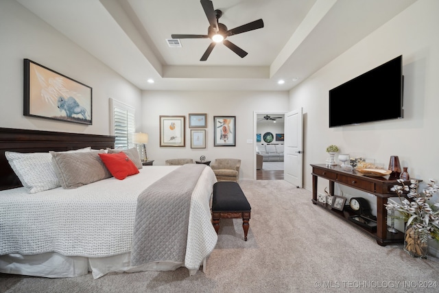 bedroom featuring carpet flooring, a tray ceiling, and ceiling fan