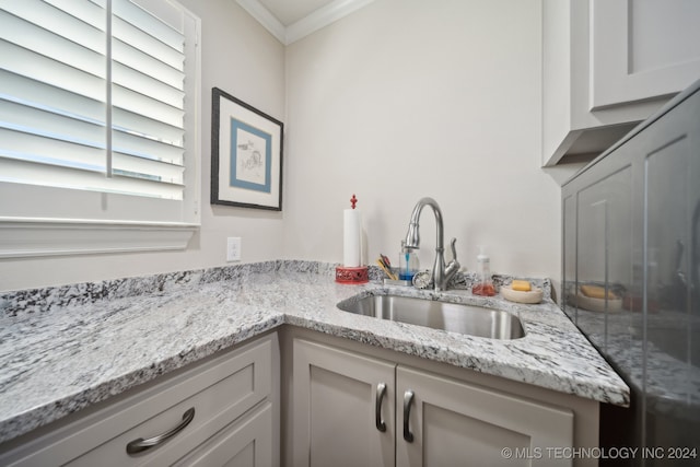 kitchen featuring ornamental molding, white cabinets, light stone counters, and sink