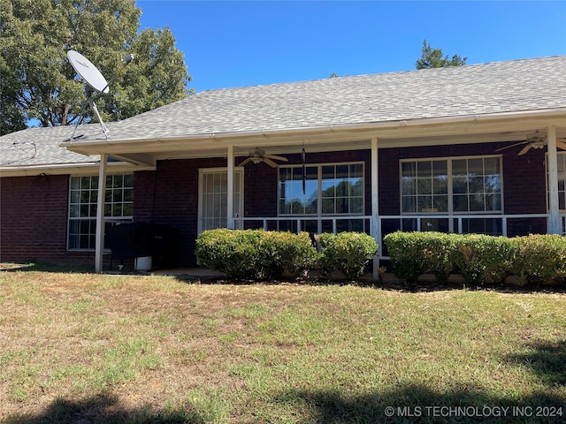 rear view of house featuring ceiling fan and a yard