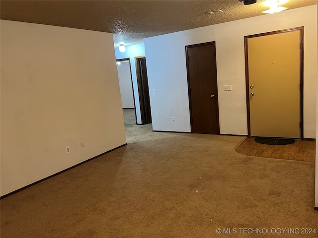 spare room with a textured ceiling and light carpet