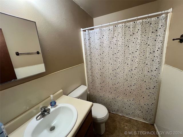 bathroom with a shower with curtain, vanity, toilet, and tile patterned floors