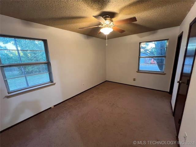 carpeted empty room with ceiling fan, a healthy amount of sunlight, and a textured ceiling