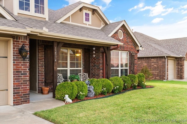 entrance to property with a garage, a porch, and a lawn