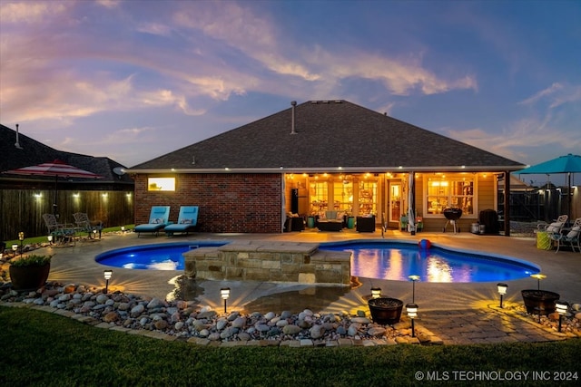 pool at dusk with a fire pit, a hot tub, and a patio area