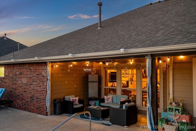 back house at dusk with an outdoor living space and a patio area