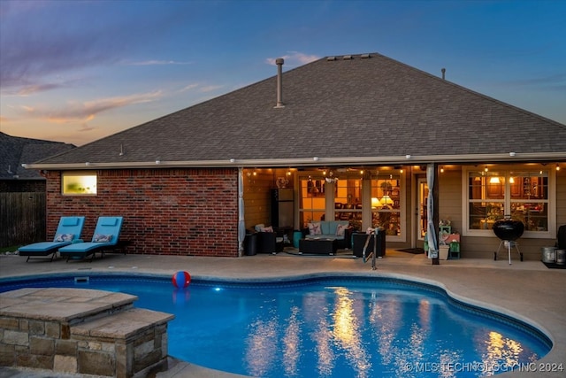 pool at dusk featuring a patio and outdoor lounge area