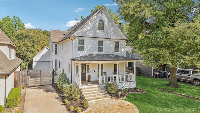 view of front of house with an outbuilding, a front lawn, covered porch, and a garage