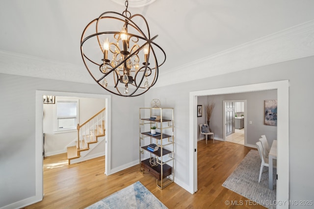 dining area with a chandelier, ornamental molding, and wood finished floors