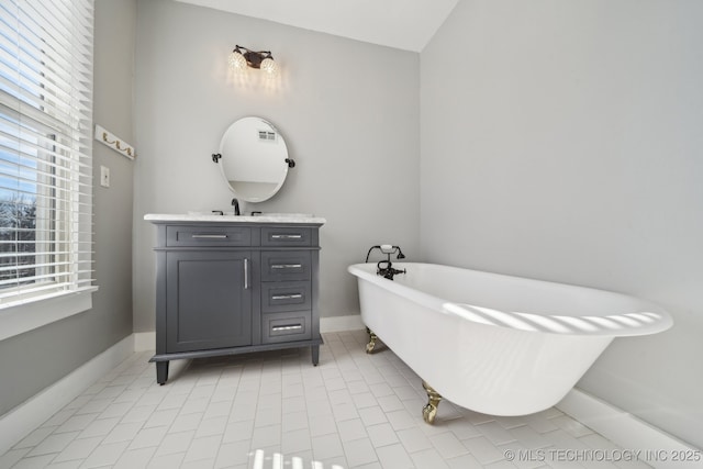 bathroom with tile patterned floors, a freestanding tub, baseboards, and vanity